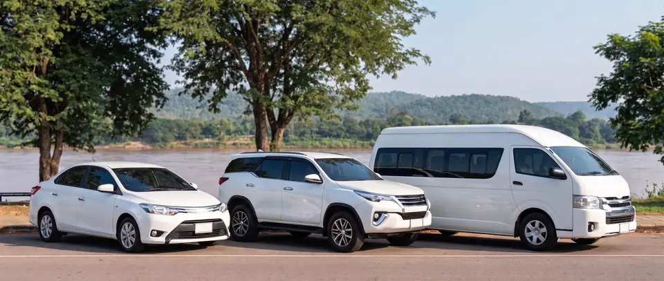 A white sedan, SUV and van parked by the Mekong at Khong Chiam